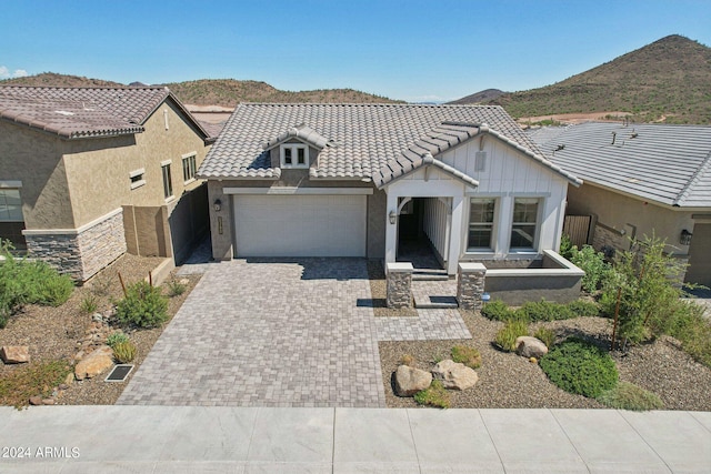 view of front of home with decorative driveway, a garage, a mountain view, and a tiled roof