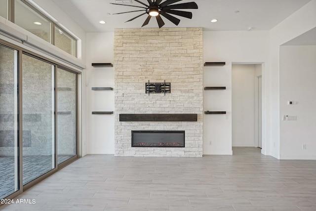 unfurnished living room with a stone fireplace, a healthy amount of sunlight, visible vents, and wood tiled floor