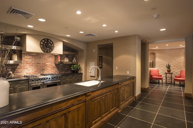 kitchen with double oven range, dark tile patterned floors, sink, and tasteful backsplash