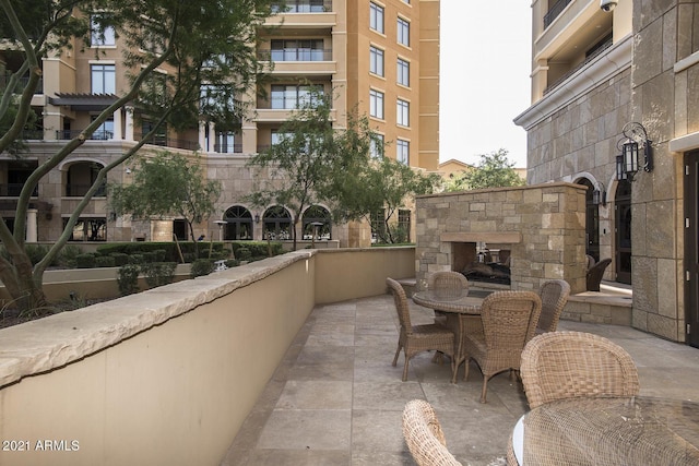 balcony with an outdoor stone fireplace and a patio area