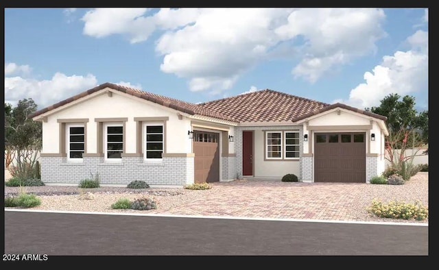 mediterranean / spanish house featuring an attached garage, a tile roof, decorative driveway, and brick siding