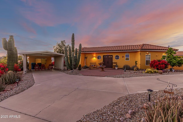view of front of home with an attached carport, stucco siding, concrete driveway, and a tile roof