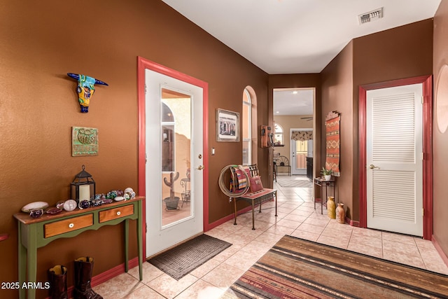 hallway with light tile patterned flooring, baseboards, and visible vents