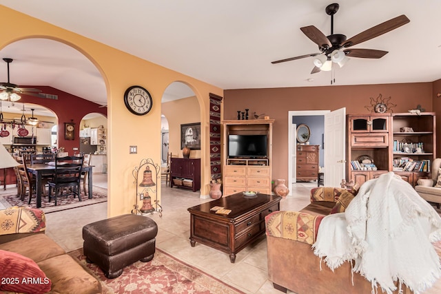 living area featuring a ceiling fan, arched walkways, light tile patterned floors, and lofted ceiling