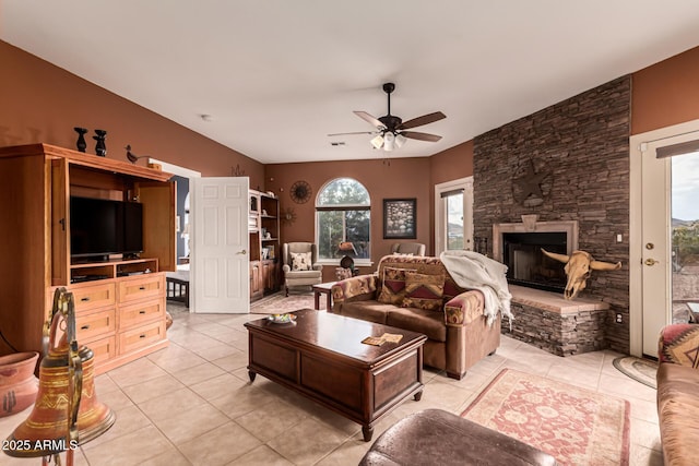 living room featuring light tile patterned floors, ceiling fan, and a fireplace