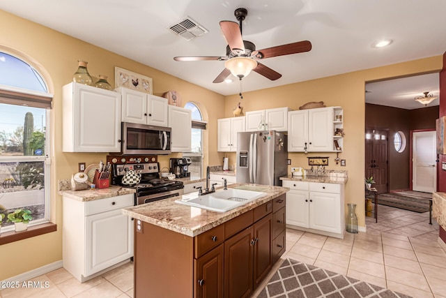 kitchen with a ceiling fan, visible vents, appliances with stainless steel finishes, a sink, and white cabinets