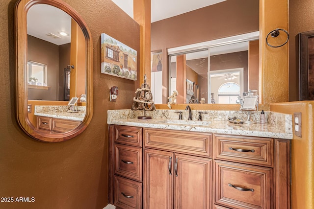 bathroom with a textured wall, visible vents, and vanity