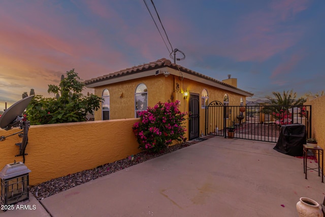 mediterranean / spanish-style house featuring fence private yard, a gate, stucco siding, and a chimney