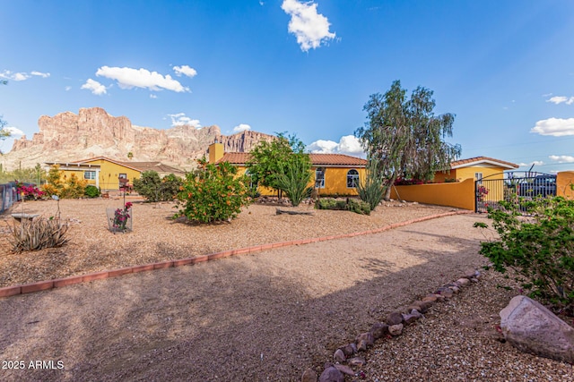 view of front of property with fence, stucco siding, a gate, a mountain view, and a tile roof