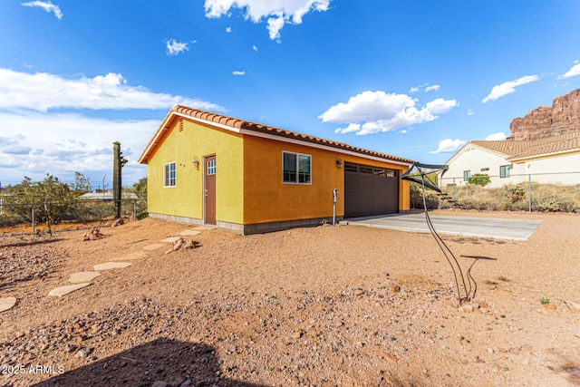 view of home's exterior featuring concrete driveway, an attached garage, fence, and stucco siding