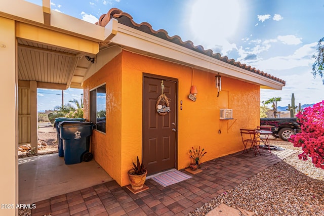 view of exterior entry featuring a wall mounted AC and stucco siding