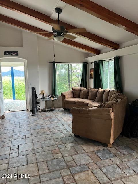 living room with vaulted ceiling with beams, plenty of natural light, and ceiling fan