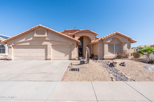 view of front of property with a tiled roof, an attached garage, driveway, and stucco siding