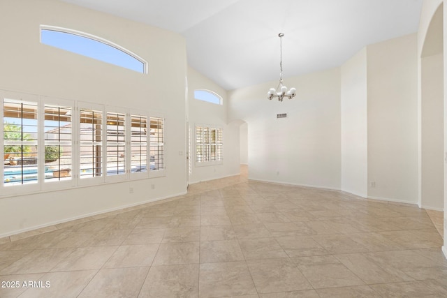 empty room with arched walkways, a notable chandelier, high vaulted ceiling, and baseboards