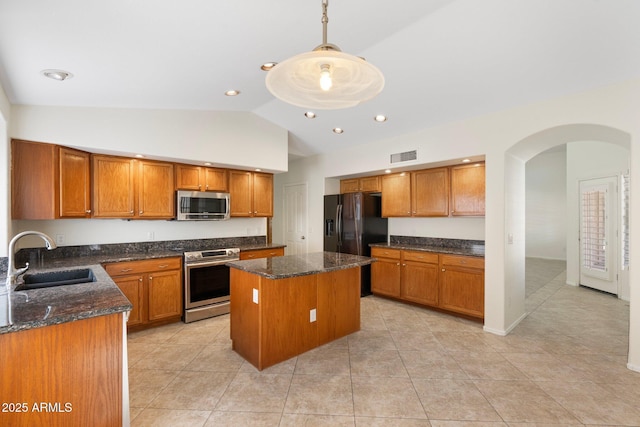 kitchen with a sink, a kitchen island, appliances with stainless steel finishes, and brown cabinetry