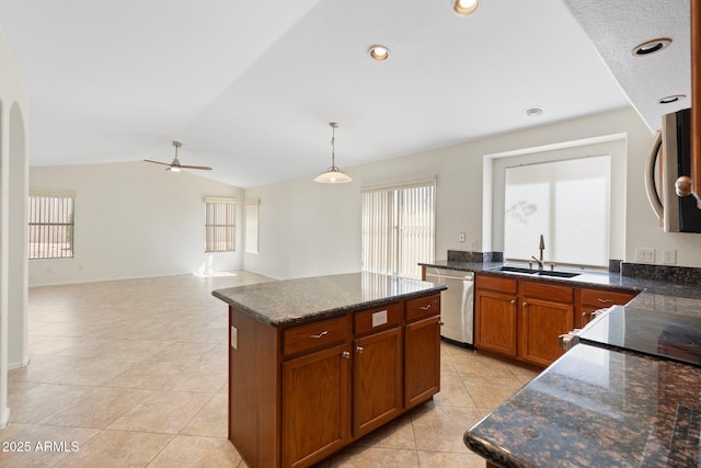 kitchen featuring vaulted ceiling, light tile patterned floors, appliances with stainless steel finishes, hanging light fixtures, and a sink