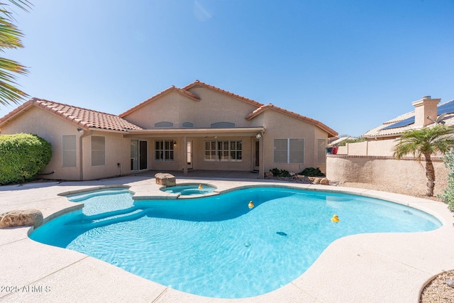 view of swimming pool featuring a pool with connected hot tub, a patio, and fence