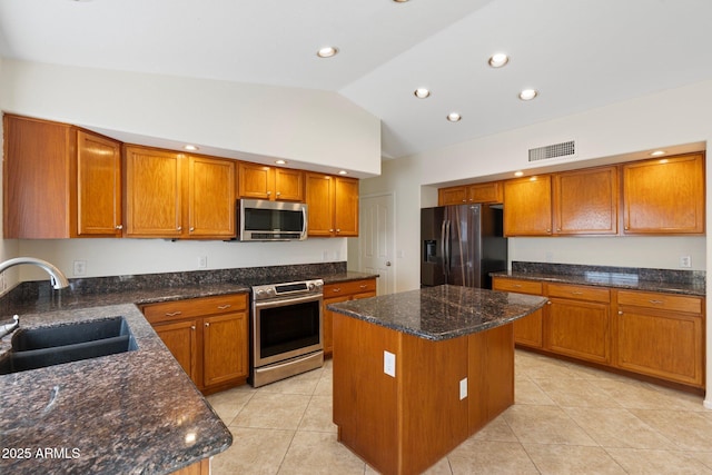 kitchen featuring brown cabinets, a kitchen island, appliances with stainless steel finishes, and a sink