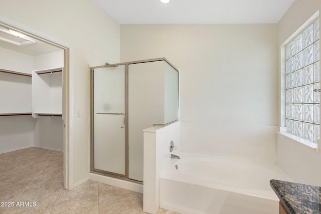 bathroom featuring baseboards, tile patterned flooring, a shower stall, a spacious closet, and a bath