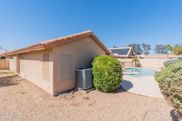 view of side of home featuring stucco siding, central AC, a fenced backyard, and a patio area