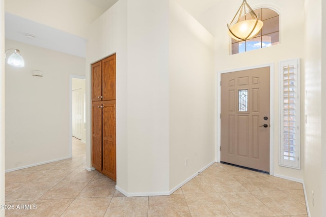 foyer entrance with light tile patterned floors, baseboards, and a towering ceiling