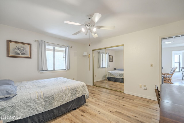 bedroom featuring a ceiling fan, a closet, baseboards, and light wood finished floors