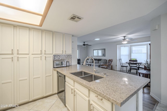 kitchen with a sink, visible vents, black dishwasher, open floor plan, and tasteful backsplash