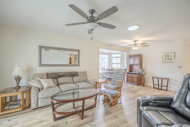 living area featuring light wood-style floors, ceiling fan, and baseboards