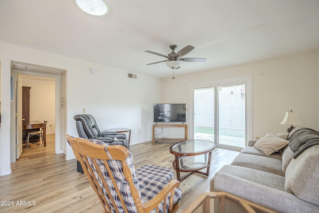 living room with light wood-style floors, visible vents, and a ceiling fan