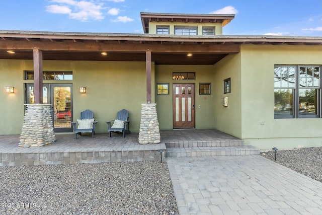 entrance to property with a porch and stucco siding