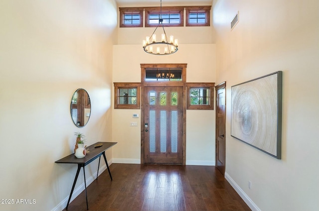 foyer entrance featuring baseboards, wood finished floors, visible vents, and a notable chandelier