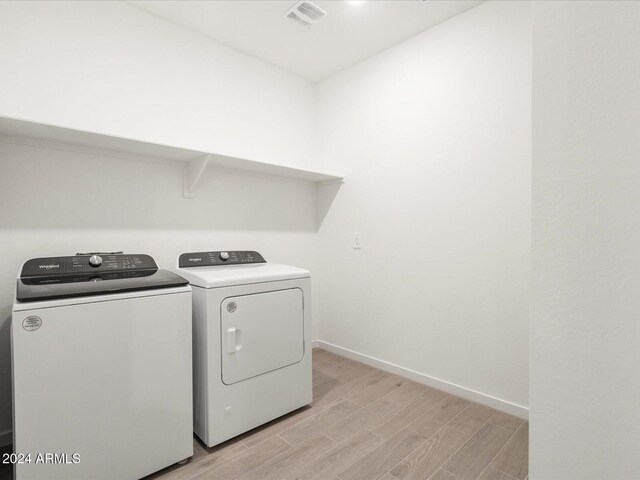 laundry room with independent washer and dryer and light hardwood / wood-style flooring