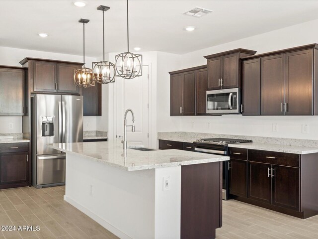 kitchen featuring dark brown cabinetry, stainless steel appliances, sink, a center island with sink, and a notable chandelier