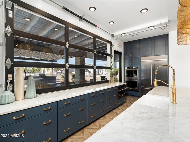 kitchen with parquet flooring, appliances with stainless steel finishes, blue cabinetry, and sink