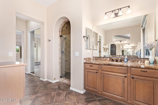 bathroom with tile patterned flooring, a shower with door, and vanity