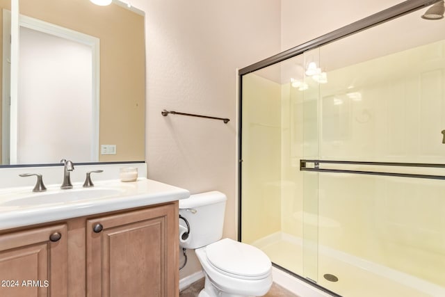 bathroom with toilet, vanity, and a shower with shower door