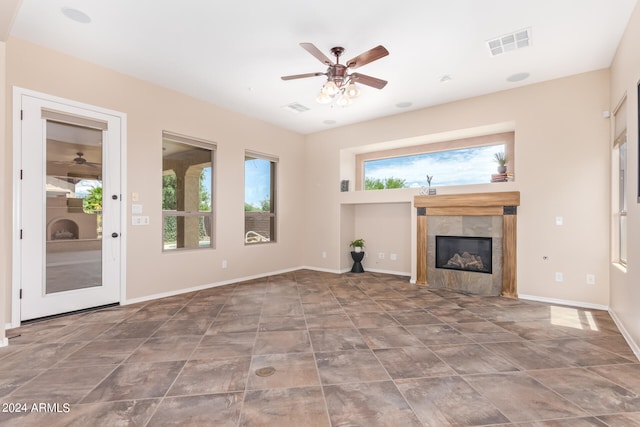 unfurnished living room with a fireplace, ceiling fan, and tile patterned flooring