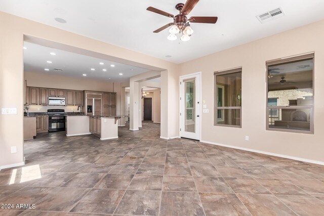 unfurnished living room featuring ceiling fan, tile patterned flooring, and sink