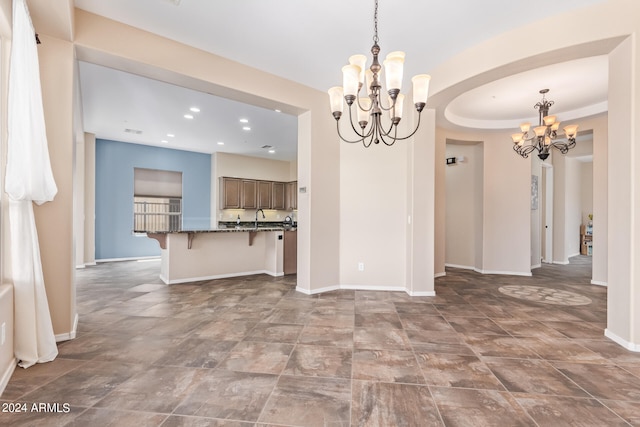 unfurnished living room featuring a raised ceiling, sink, an inviting chandelier, and tile patterned flooring