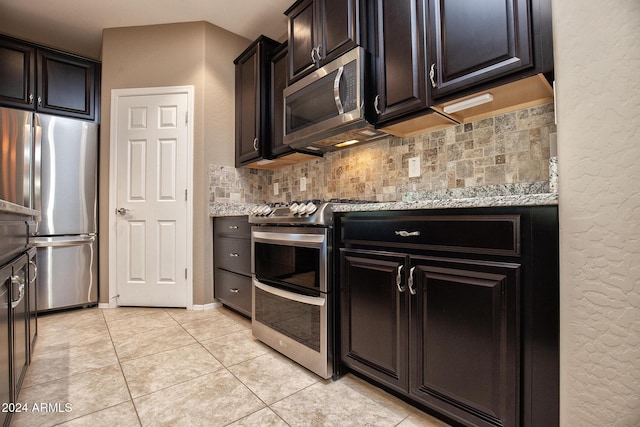 kitchen with stainless steel appliances, tasteful backsplash, light stone countertops, and light tile patterned floors