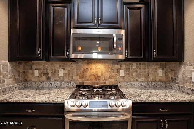 kitchen with tasteful backsplash, dark brown cabinets, appliances with stainless steel finishes, and light stone counters