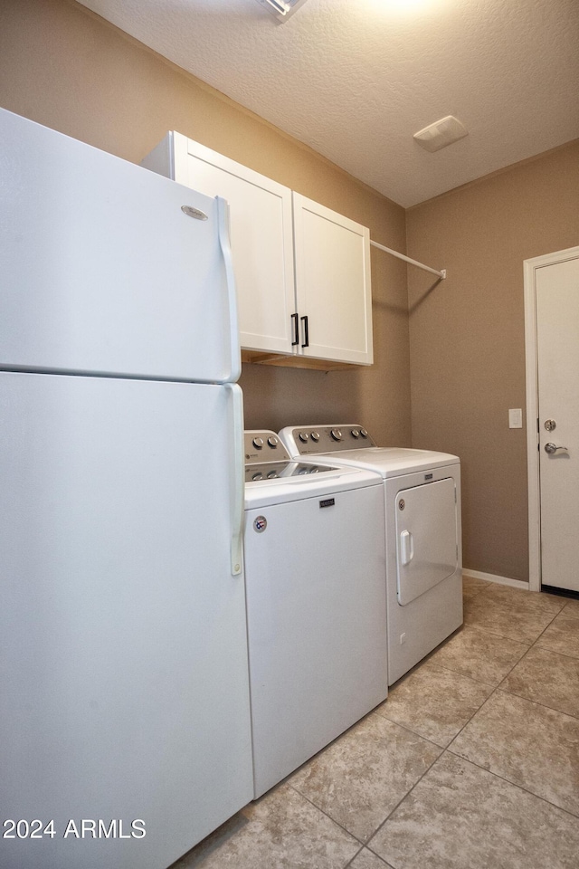 laundry room with cabinets, separate washer and dryer, a textured ceiling, and light tile patterned floors