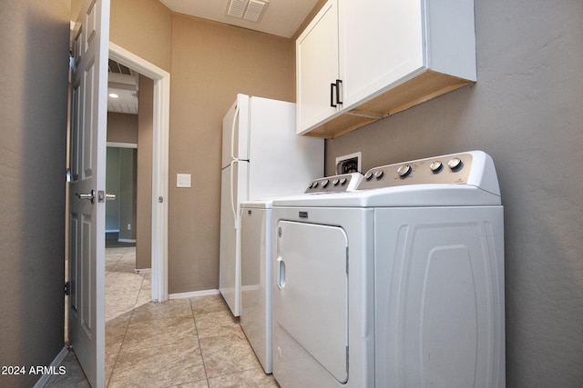 clothes washing area featuring cabinets, light tile patterned floors, and washer and dryer