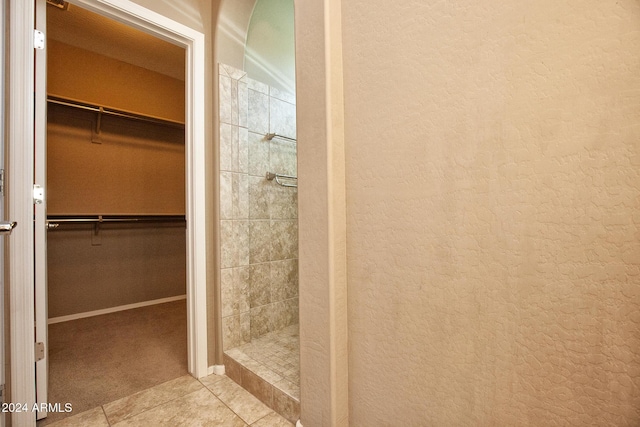 bathroom with a tile shower and tile patterned floors