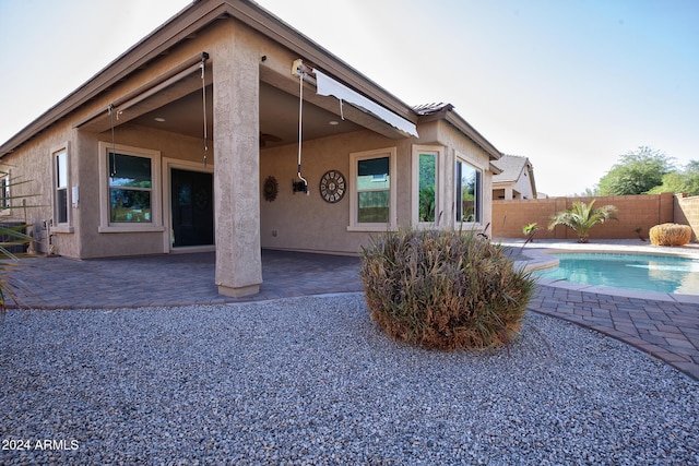 rear view of property with a fenced in pool and a patio