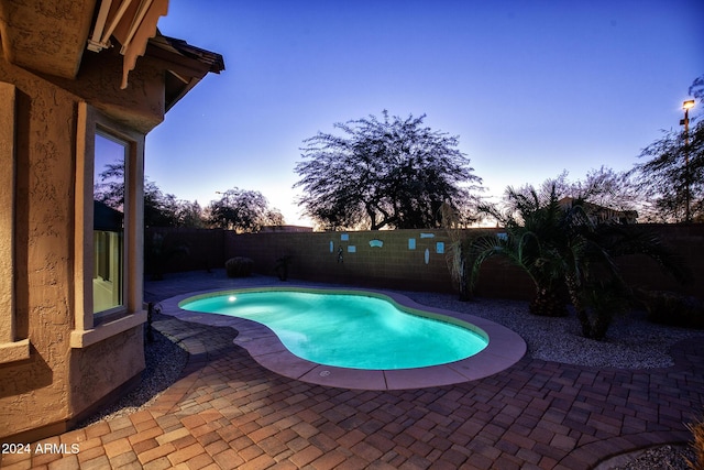 pool at dusk featuring a patio area