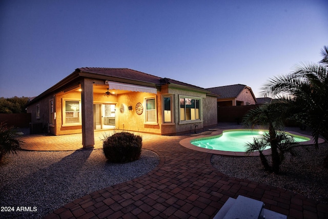 back house at dusk featuring a fenced in pool, a patio, and ceiling fan