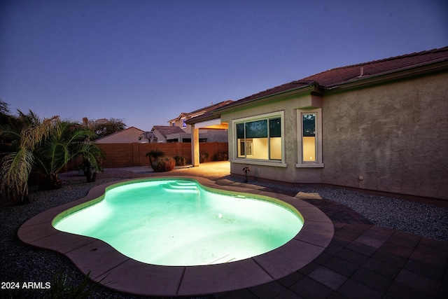 pool at dusk featuring a patio