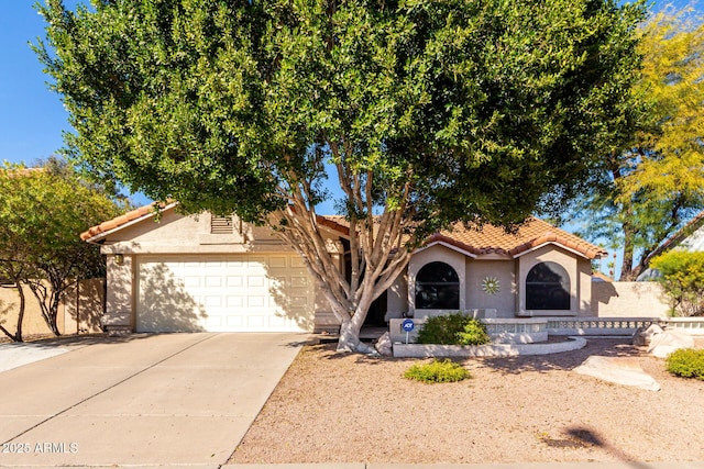 view of front of home featuring a garage, a tiled roof, driveway, and stucco siding