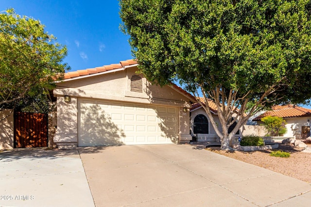 view of front of home featuring an attached garage, a tiled roof, concrete driveway, and stucco siding